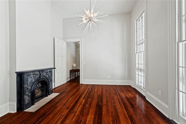 unfurnished living room featuring an inviting chandelier and dark hardwood / wood-style floors