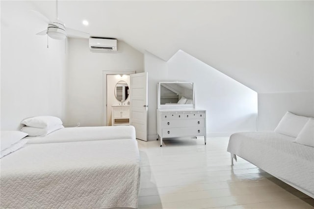 bedroom with ceiling fan, a wall mounted AC, vaulted ceiling, and ensuite bath