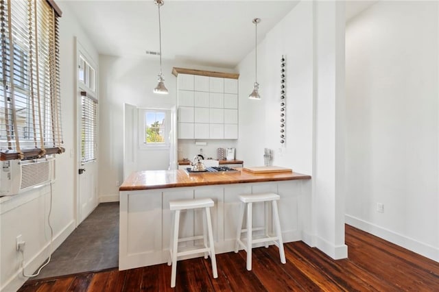 kitchen with hanging light fixtures, kitchen peninsula, a kitchen bar, white cabinets, and dark hardwood / wood-style flooring