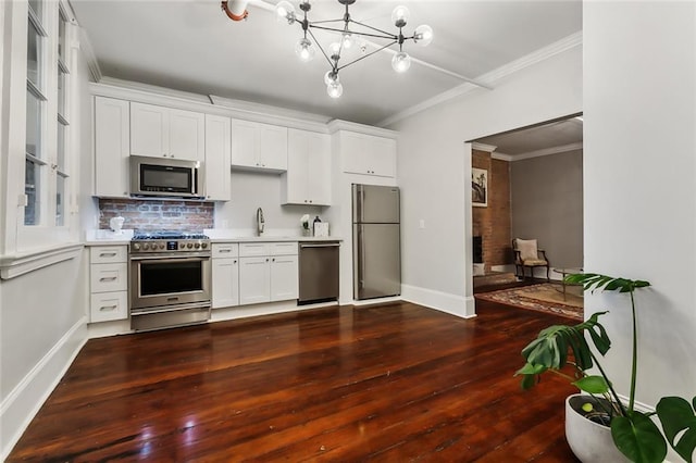 kitchen with appliances with stainless steel finishes, white cabinets, dark wood-type flooring, crown molding, and an inviting chandelier