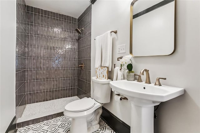 bathroom with tiled shower, toilet, and tile patterned flooring