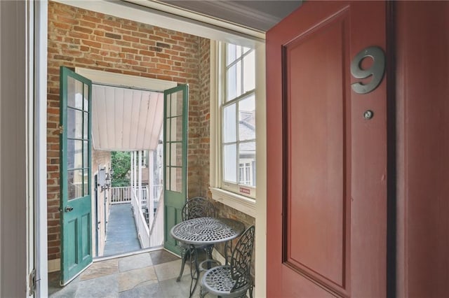 entryway featuring stone finish flooring, brick wall, and a wealth of natural light