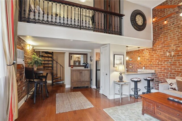 entrance foyer with a towering ceiling, wood finished floors, brick wall, baseboards, and stairway