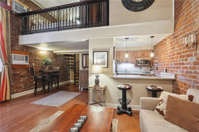 living room with baseboards, wood finished floors, and brick wall