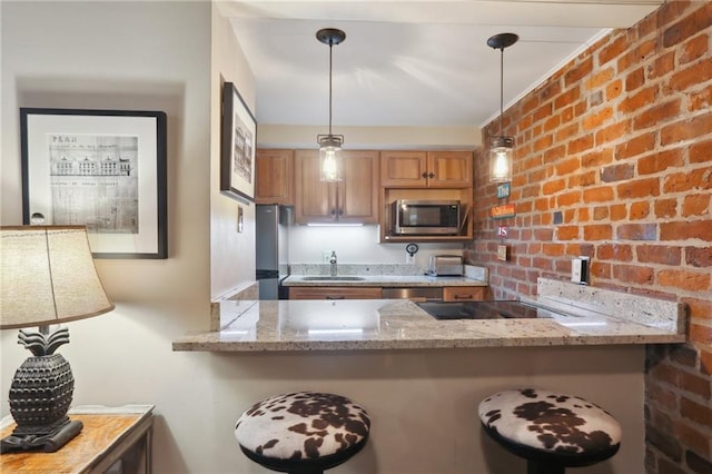 kitchen featuring light stone countertops, decorative light fixtures, and brick wall