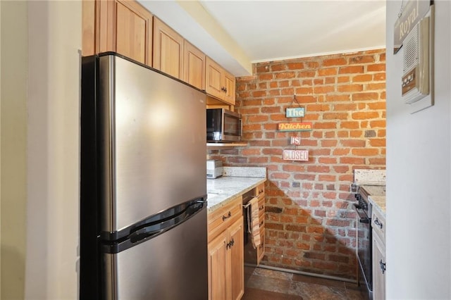 kitchen with brick wall, black appliances, light brown cabinetry, and light stone counters