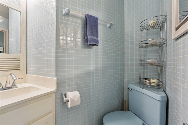 bathroom with toilet, vanity, and tile walls