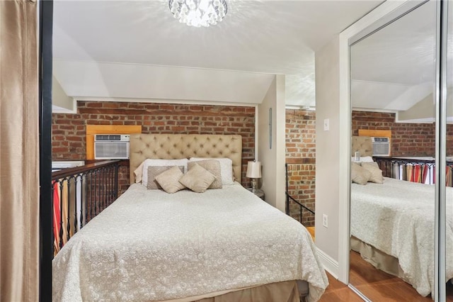 bedroom with brick wall, a wall mounted AC, and hardwood / wood-style floors