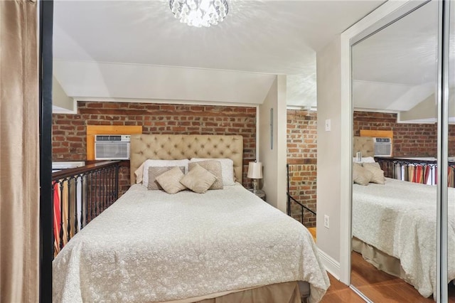 bedroom featuring an AC wall unit, brick wall, and wood finished floors