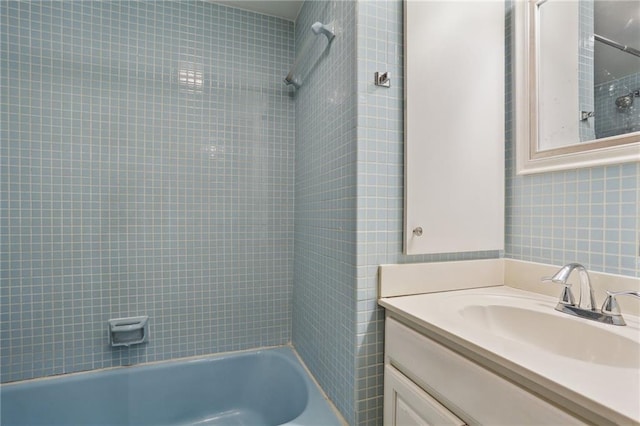 bathroom featuring vanity, tiled shower / bath combo, and tile walls