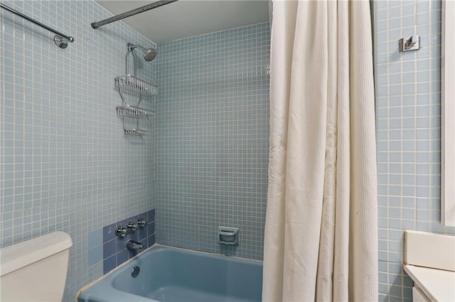 full bath featuring shower / bath combo with shower curtain, toilet, and tile walls