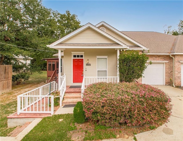 605 Florida St, Mandeville, LA 70448 - shotgun-style home with an attached garage, concrete driveway, covered porch, a shingled roof, and brick siding