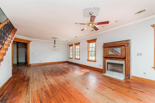 unfurnished living room featuring hardwood / wood-style flooring, ornamental molding, ceiling fan with notable chandelier, and a premium fireplace