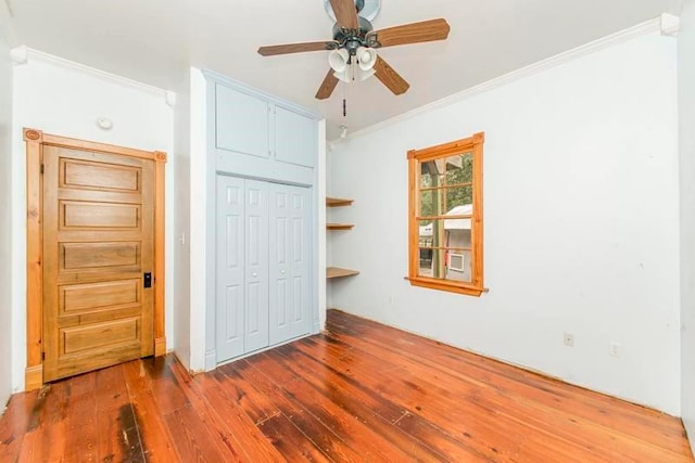 unfurnished bedroom with a closet, ornamental molding, wood-type flooring, and ceiling fan