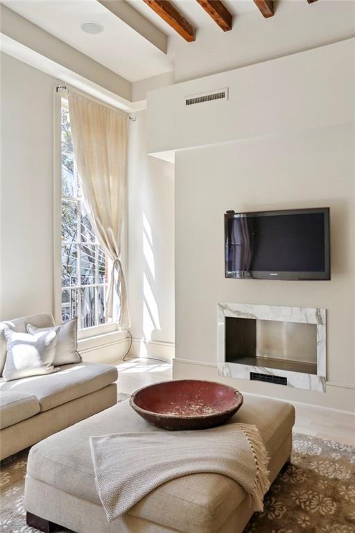 living room featuring a fireplace, beamed ceiling, and a wealth of natural light