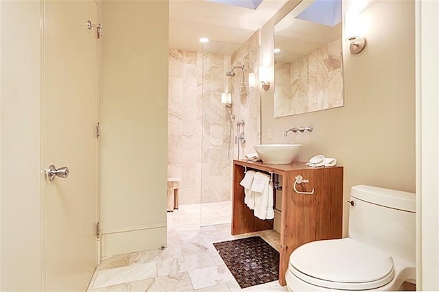 bathroom with a tile shower, vanity, and toilet