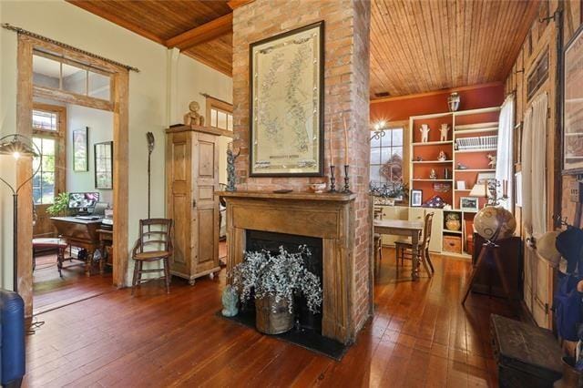 sitting room with a fireplace, beam ceiling, dark hardwood / wood-style floors, and wooden ceiling