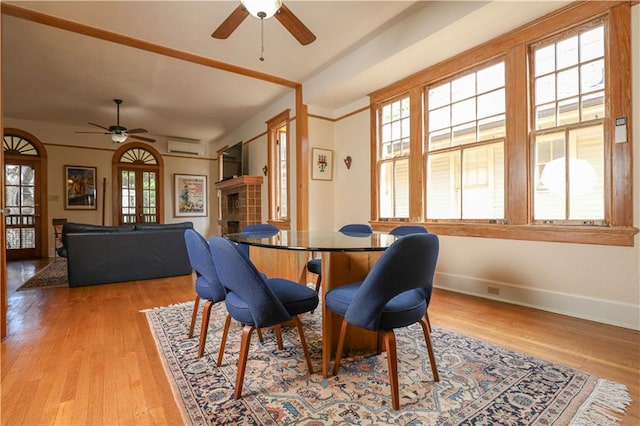 dining area with light hardwood / wood-style flooring, a wall unit AC, and ceiling fan