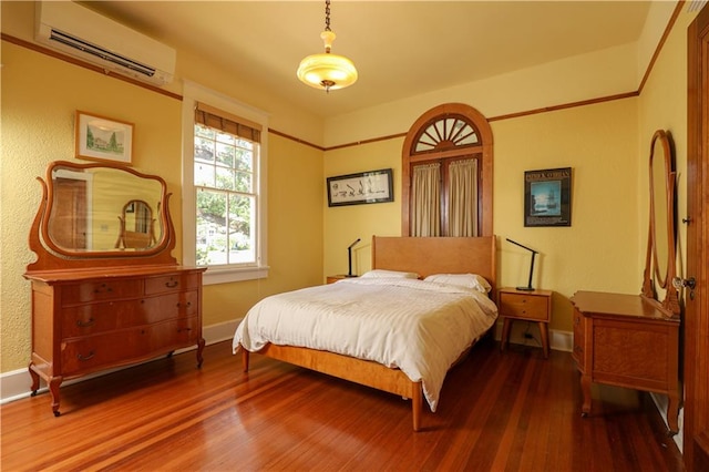 bedroom with hardwood / wood-style flooring and a wall unit AC