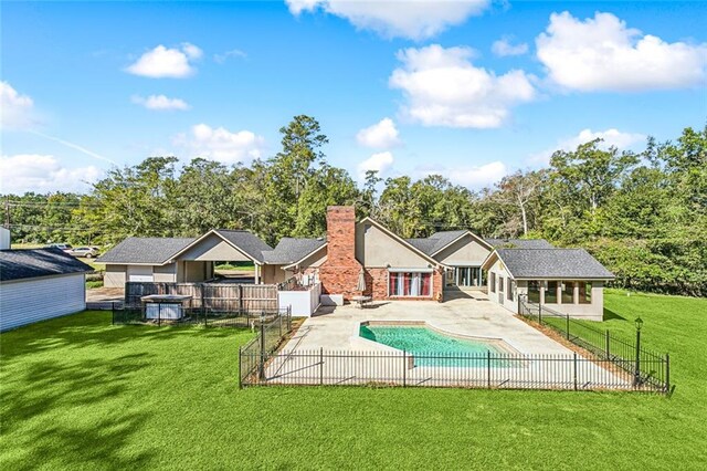 rear view of house featuring a yard, a patio area, and a fenced in pool