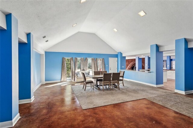 dining area featuring lofted ceiling, concrete flooring, and a textured ceiling