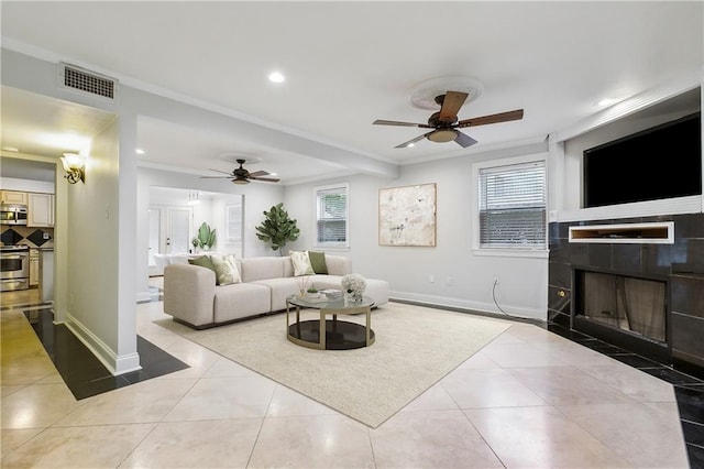 tiled living room featuring ceiling fan, ornamental molding, and a fireplace