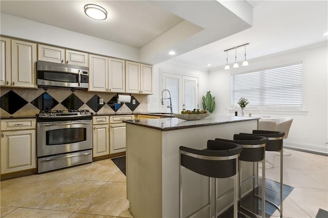 kitchen with decorative backsplash, stainless steel appliances, sink, a center island, and pendant lighting