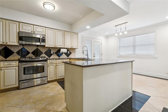 kitchen with hanging light fixtures, stainless steel appliances, backsplash, sink, and a center island