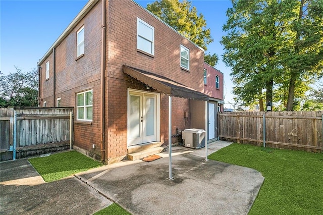 rear view of house with a patio, central AC, and a yard