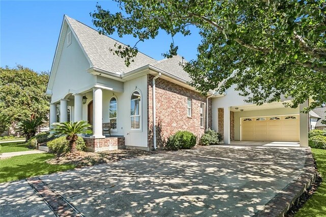view of front of property featuring roof with shingles, brick siding, driveway, and an attached garage