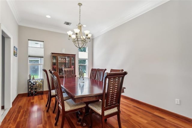 dining room with ornamental molding, hardwood / wood-style flooring, and an inviting chandelier