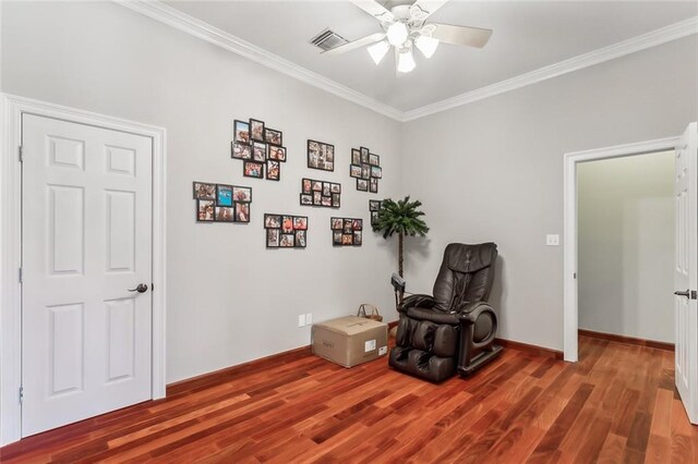 living area with baseboards, a ceiling fan, crown molding, visible vents, and wood finished floors