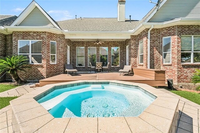 rear view of house featuring roof with shingles, a ceiling fan, an in ground hot tub, and brick siding