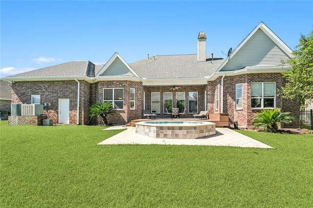 rear view of house with a patio area, an in ground hot tub, and a lawn