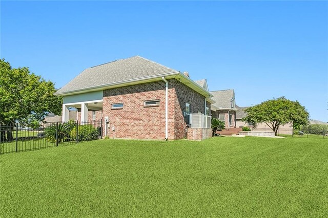 back of property with brick siding, fence, a lawn, and roof with shingles