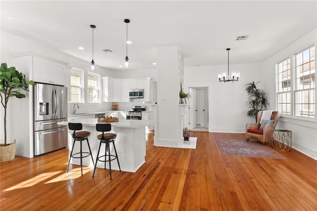 kitchen with appliances with stainless steel finishes, white cabinetry, sink, and light wood-type flooring