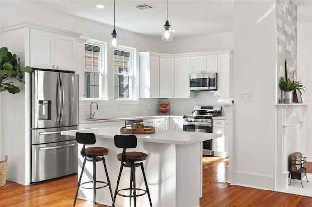 kitchen featuring appliances with stainless steel finishes, sink, a kitchen island, and white cabinets