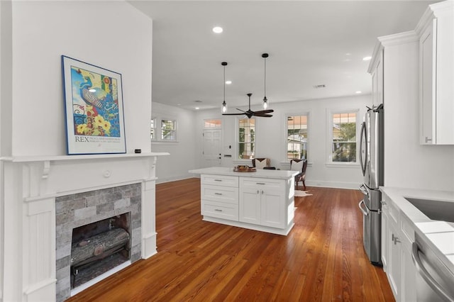 kitchen featuring stainless steel appliances, decorative light fixtures, dark hardwood / wood-style flooring, white cabinets, and ceiling fan