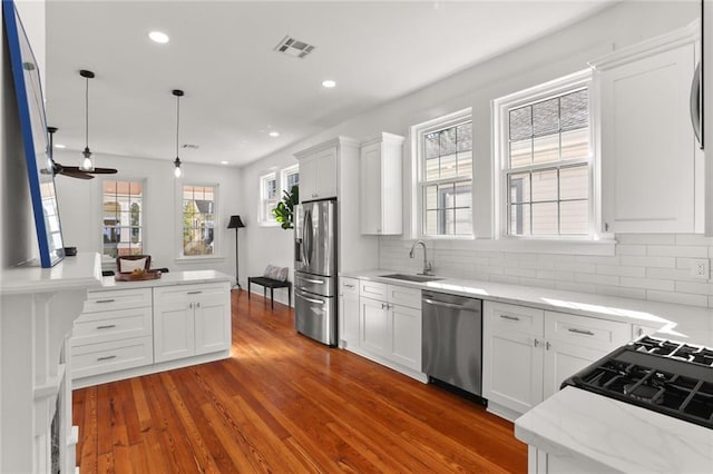 kitchen featuring decorative backsplash, dark wood-type flooring, white cabinets, decorative light fixtures, and appliances with stainless steel finishes