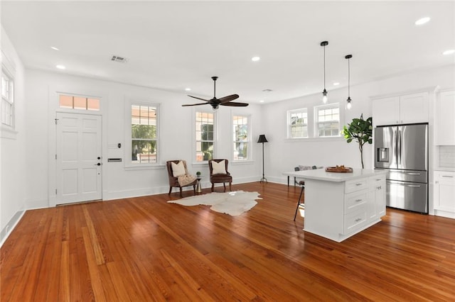 kitchen with hardwood / wood-style floors, a center island, stainless steel fridge with ice dispenser, and white cabinetry