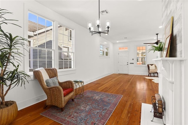 living area with a wealth of natural light, hardwood / wood-style floors, and ceiling fan with notable chandelier