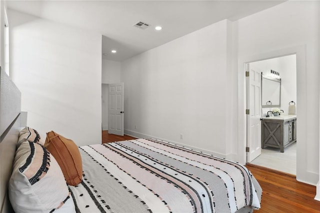 bedroom featuring dark wood-type flooring and ensuite bath