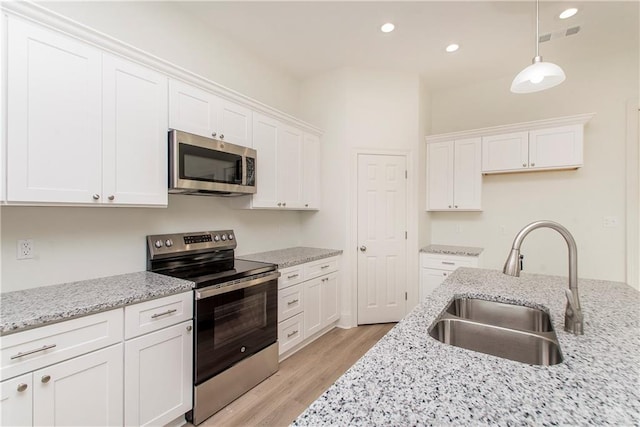 kitchen featuring stainless steel appliances, white cabinets, sink, and light wood-type flooring