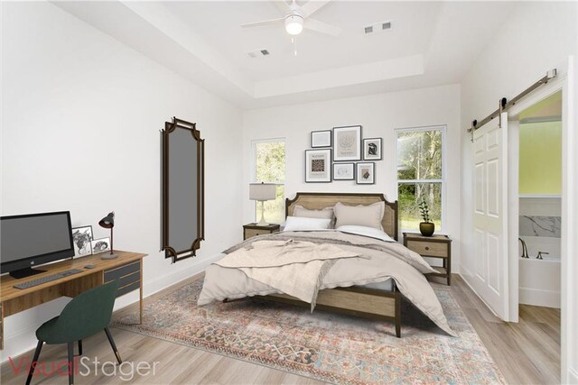 bedroom featuring light hardwood / wood-style floors, a barn door, multiple windows, and ceiling fan