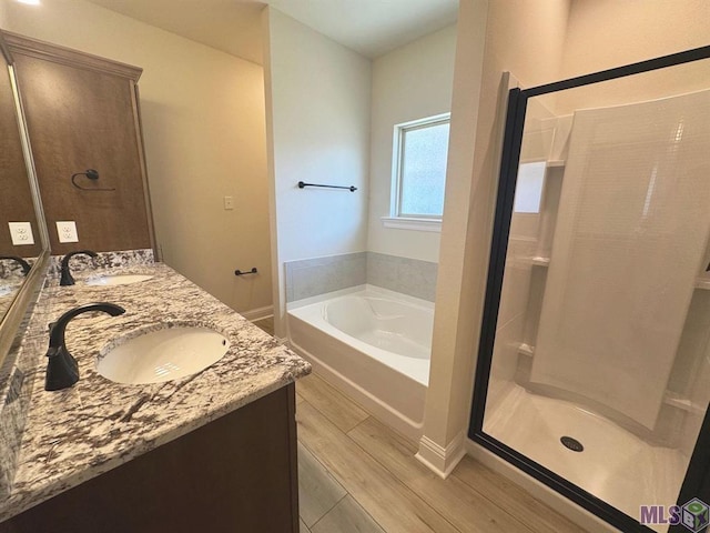 bathroom featuring double vanity, a sink, a stall shower, and a garden tub