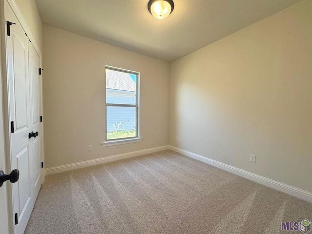 unfurnished room featuring light carpet and baseboards