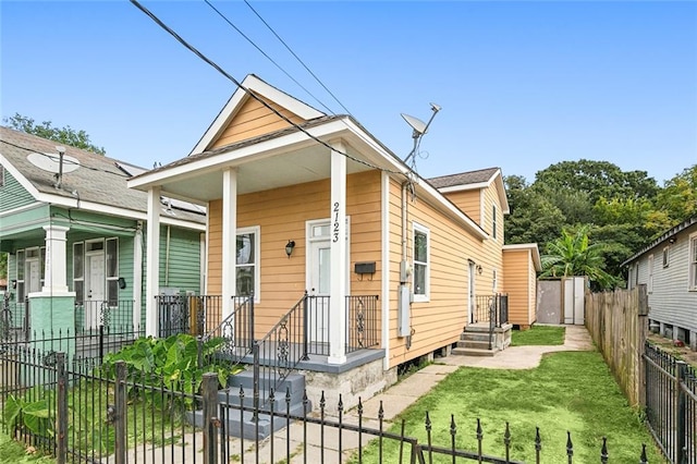 shotgun-style home with a fenced front yard, a porch, and a front yard