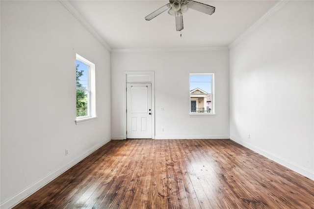 empty room with hardwood / wood-style floors, crown molding, and baseboards