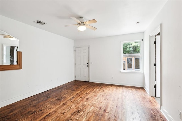 empty room with visible vents, baseboards, hardwood / wood-style floors, and a ceiling fan