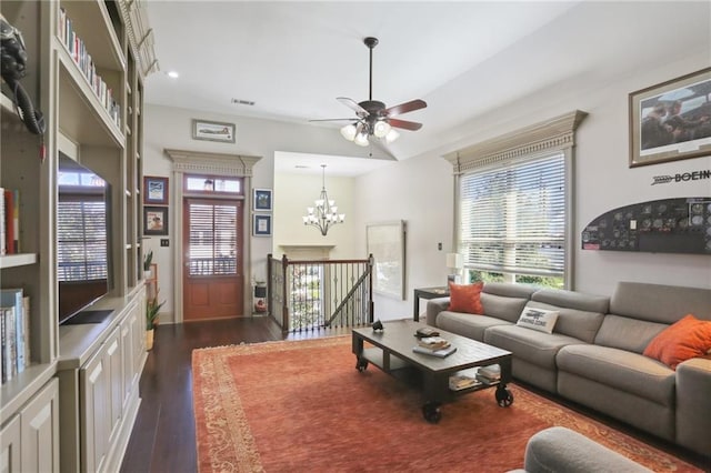 living room featuring ceiling fan with notable chandelier and dark hardwood / wood-style flooring